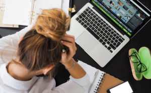 Managing stress at work, lady holding head in stress by computer