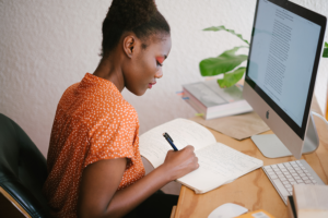 Top 3 Tips To Self-Heal Your Brand, image of a woman at her desk with notes next to a computer